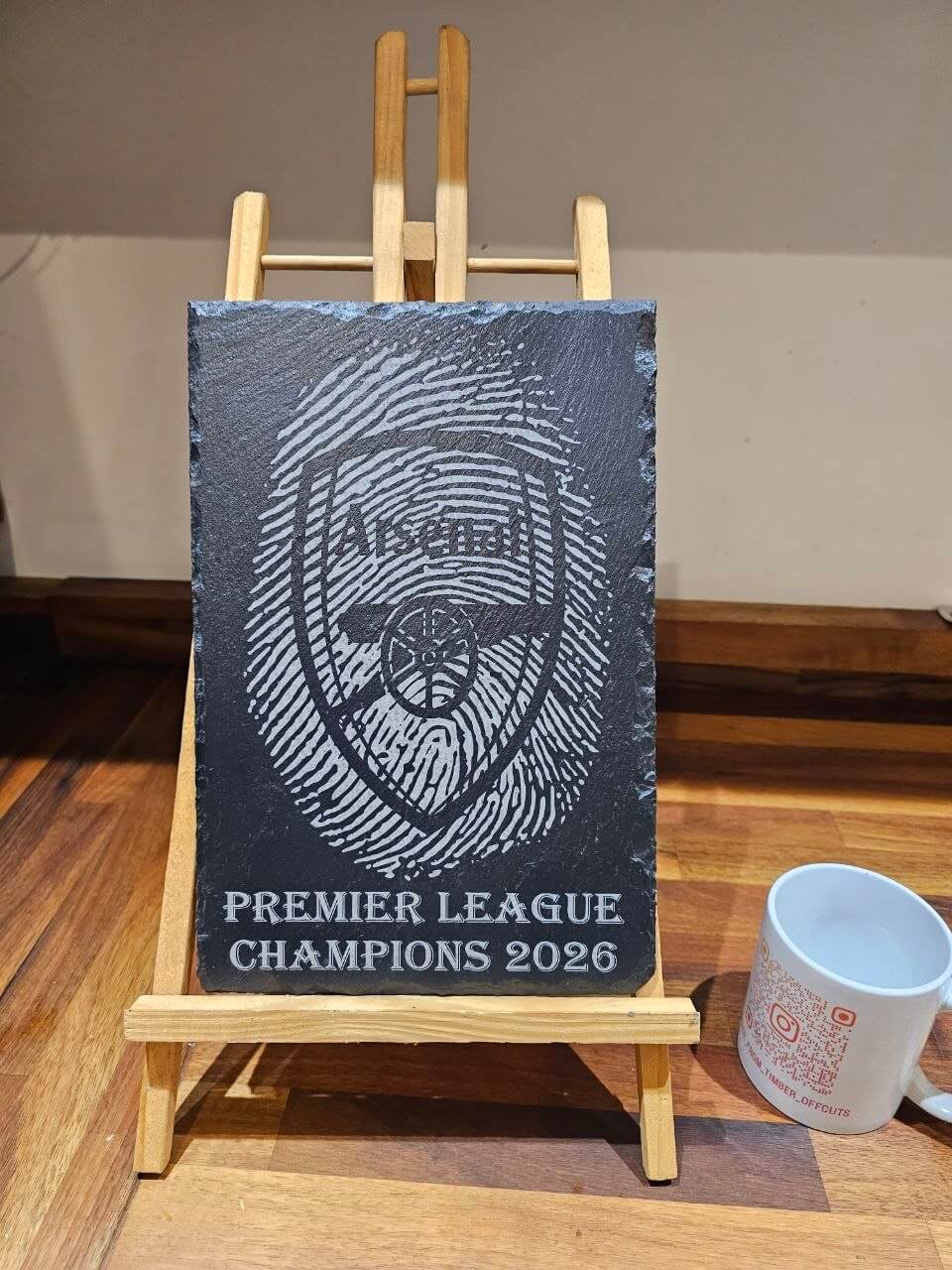 Arsenal Premier League Champions 2026 Fingerprint Plaque displayed on a wooden easel, showcasing the commemorative design.