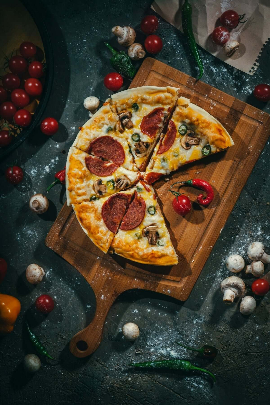A sliced pepperoni and mushroom pizza on a wooden board.