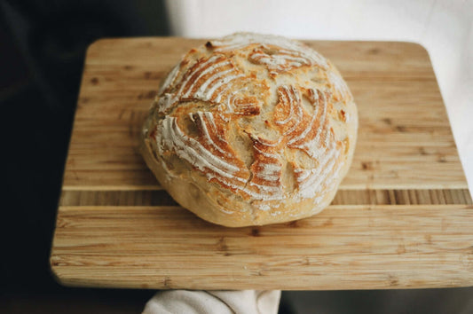 a loaf of bread sitting on top of a wooden cutting board