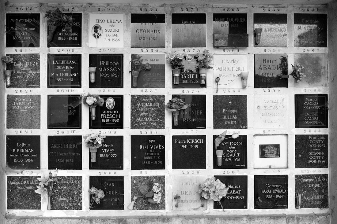 Black and white wall of memorial plaques with flowers