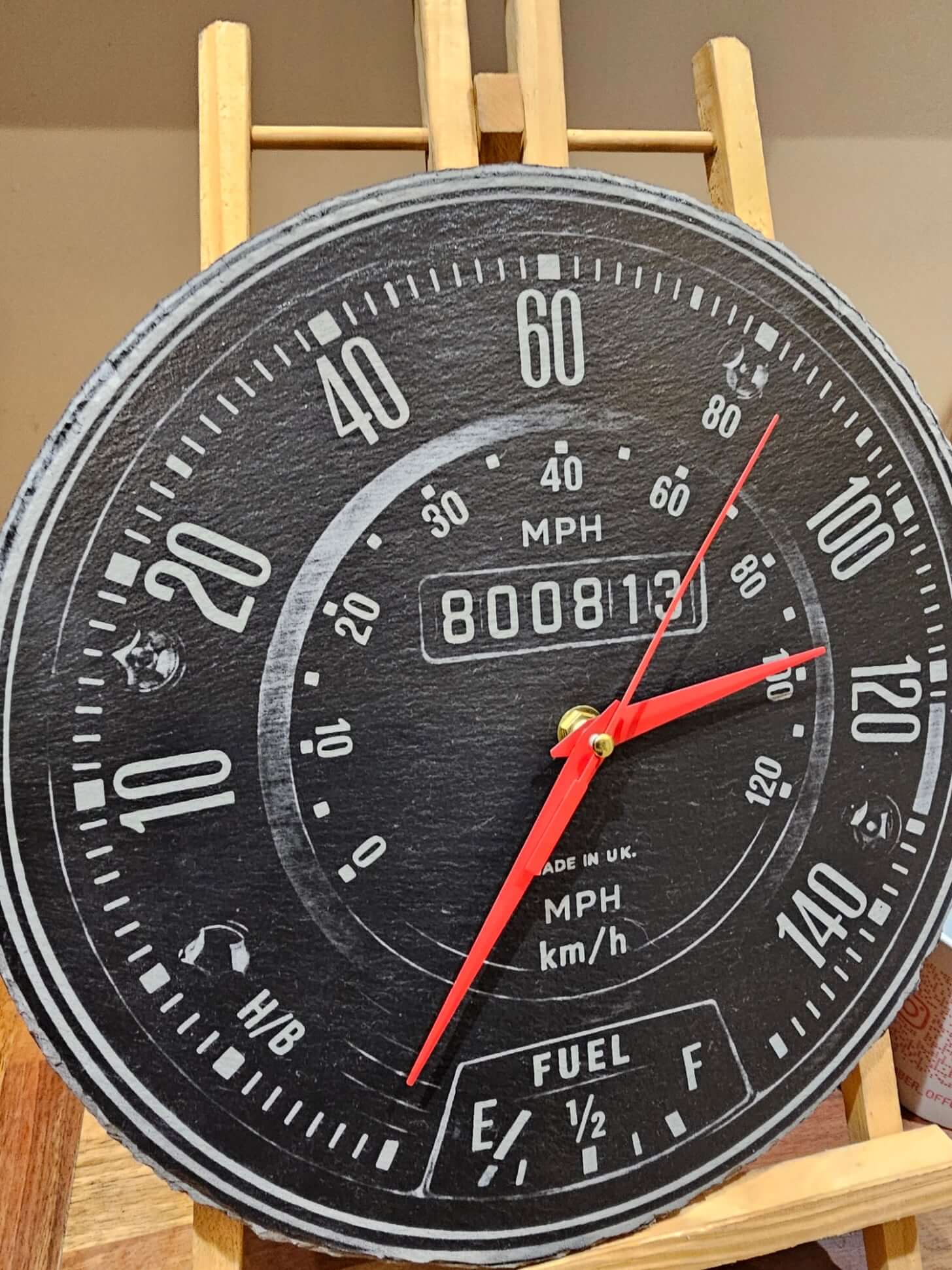 Engraved Slate Clock showing speedometer design with red hands and fuel gauge on a wooden easel.