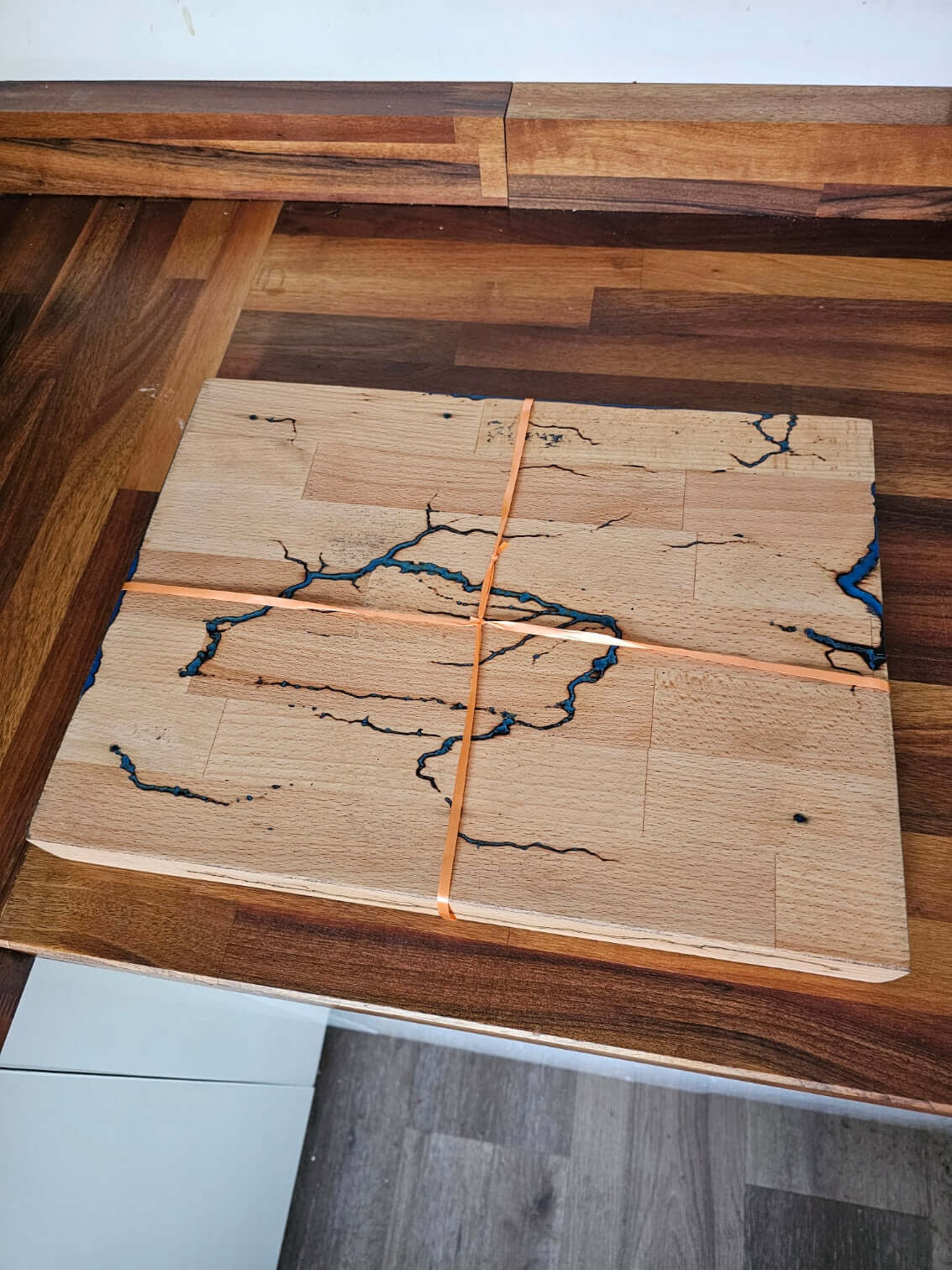 Handmade Multi-Colour Fractal Burn Chopping Board on wooden countertop with blue running patterns