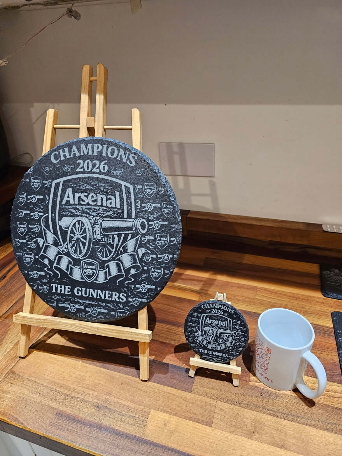 Arsenal Champions 2026 Engraved 300mm Round Slate Plaque on display with cup and smaller plaque