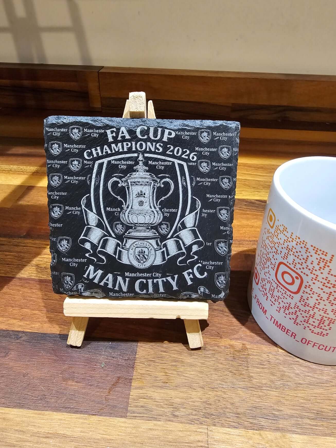 Manchester City FA Cup Champions 2026 Slate Coaster displayed on an easel with decorative design.