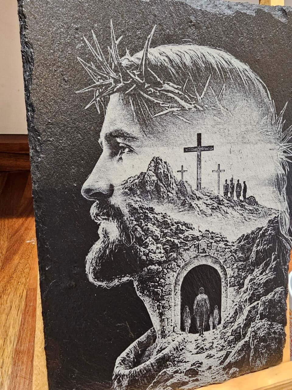 Slate plaque featuring an artistic engraving of Jesus with a crown of thorns and a landscape of crosses.