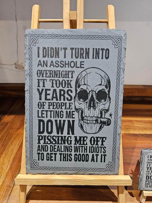 I Didn’t Turn Into an Asshole Overnight slate plaque. 30x20cm with bold skull illustration and humorous quote.